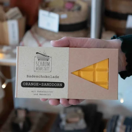 orangefarbene Badeschokolade Orange-Sanddorn in Karton-Verpackung wird in der Hand gehalten