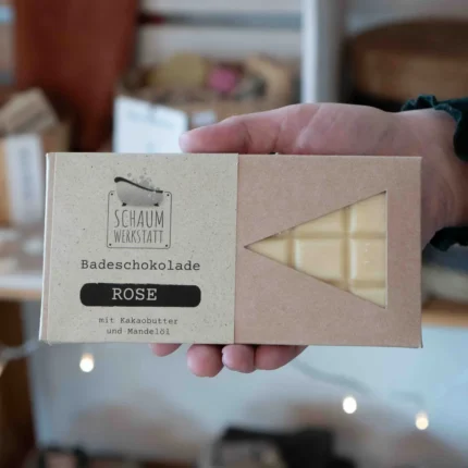 cremfarbene Badeschokolade Rose in Karton-Verpackung wird in der Hand gehalten