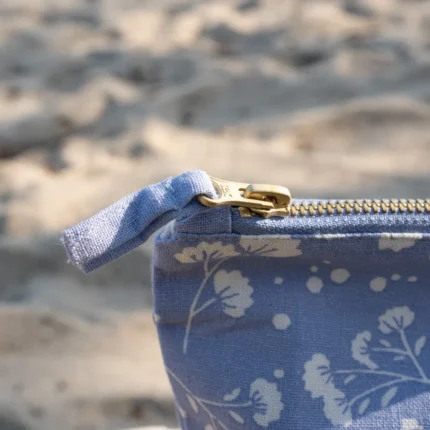 Blaue Kosmetiktasche mit Blütenmuster am Strand