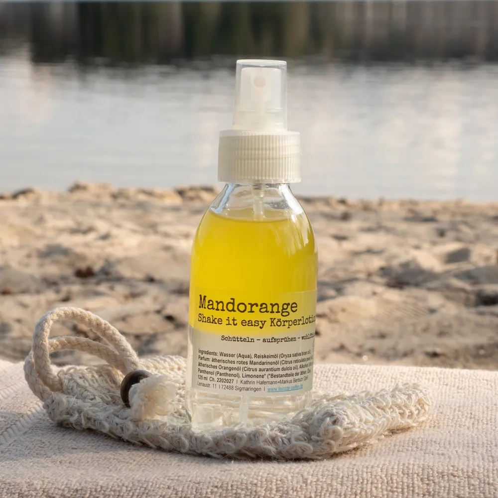 lotion-orange Body Lotion in einer Glasflasche mit Spray Funktion am Strand arrangiert